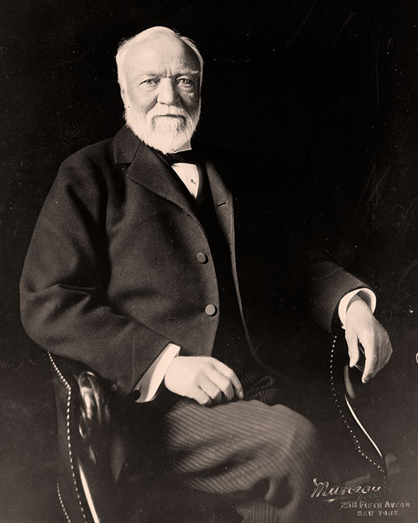 Andrew Carnegie has a white beard and wears a suit.