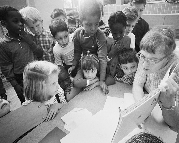 A teacher shows her class a book.