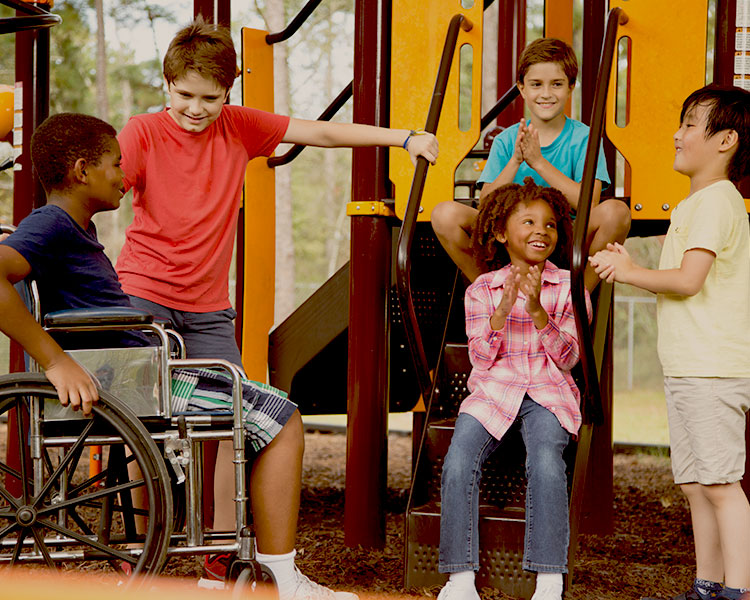 Five kids smile and laugh on a playground.