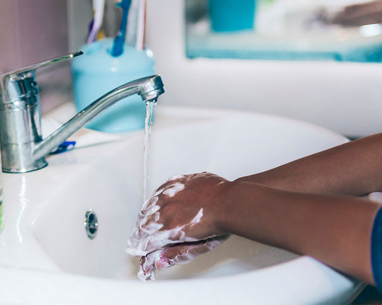 Someone washes their hands with soap under a faucet.