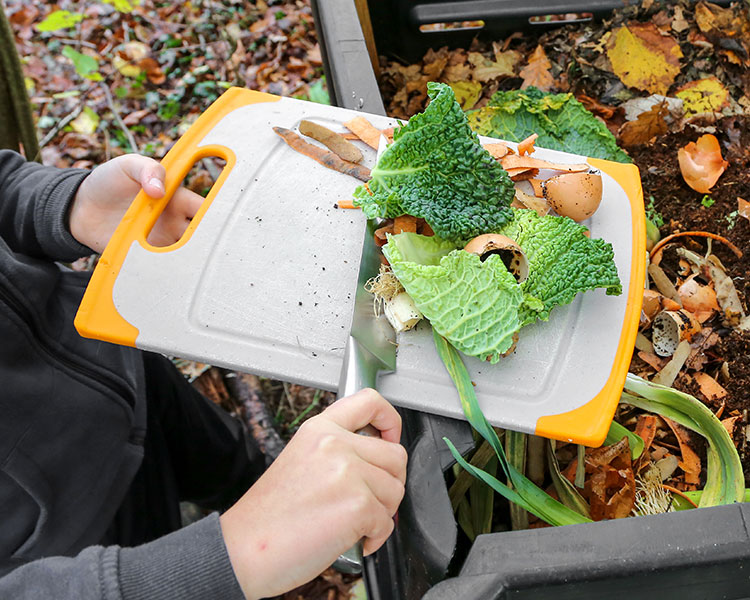 Someone putting food scraps into a compost