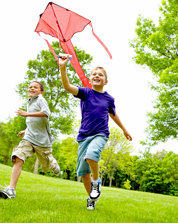 Two boys running with a kite