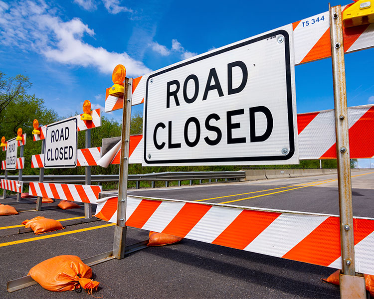 A orange and white barrier with a "Road Closed" sign