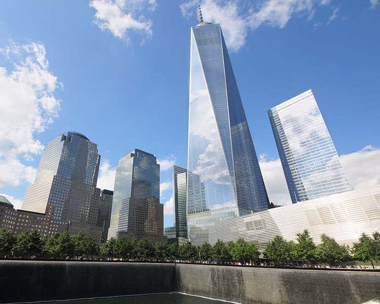 A ground point of view of tall glass buildings reaching into blue clear skies