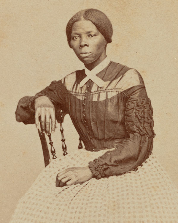 Black and white photo of a woman in a dress sitting in a chair posing for the photo