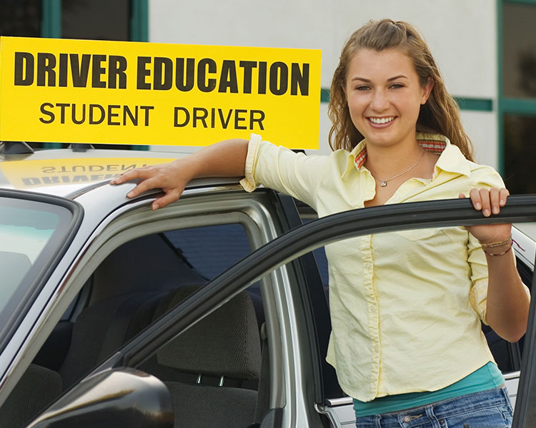Teenager smiling next to a car. Text reads: Driver Education Student Driver