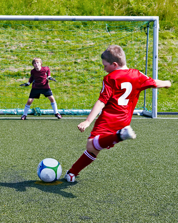 Kid soccer playing shooting on the goalie