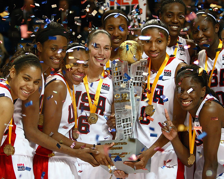 Women&apos;s USA Basketball team celebrating with a large trophy