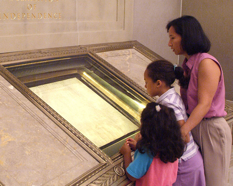 A mother and her children looking at a document on display in a museum