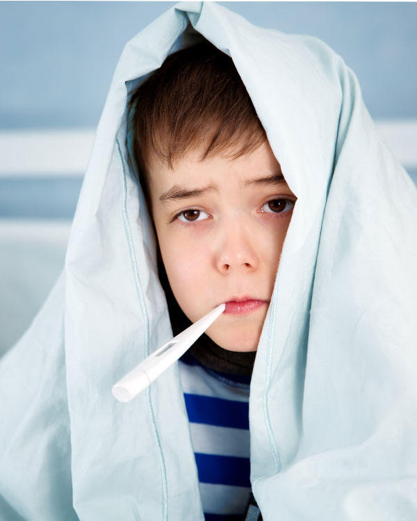 Sick child with blanket over head and thermometer in mouth