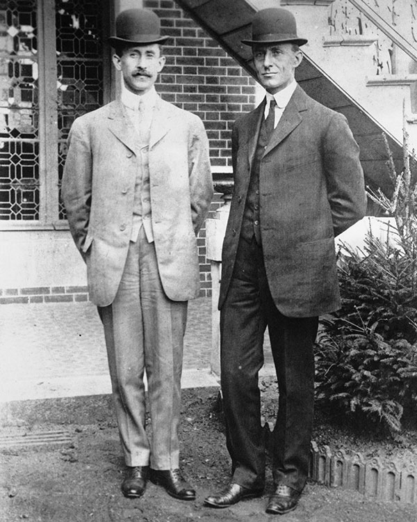 Black & white photo of the Wright Brothers posing & wearing suits