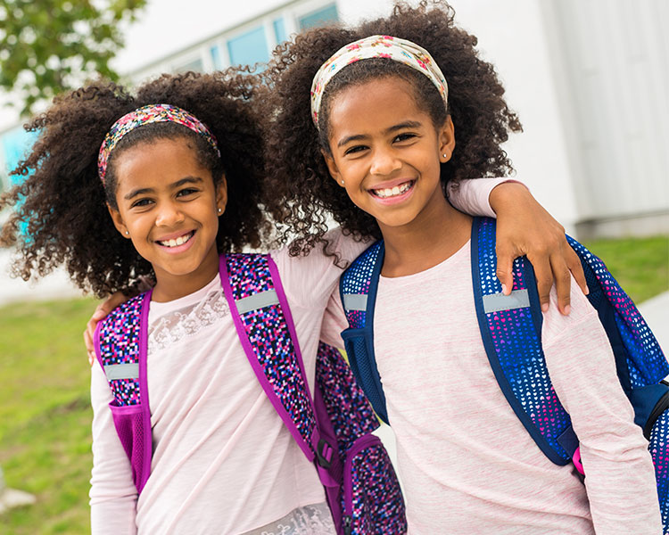 Photo of two twin students wearing book bags