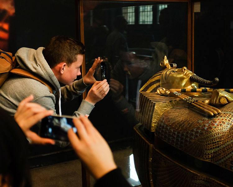 Photo of a person taking a photo of an Egyptian sarcophagus in a museum