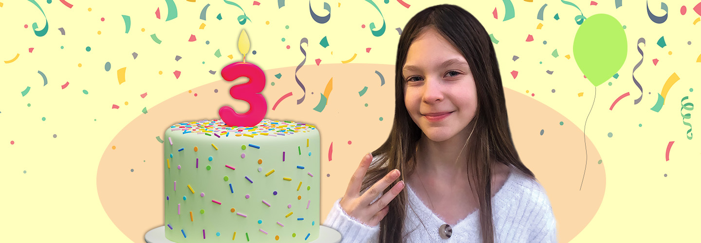 Image of a person holding up three fingers while standing next to cake decorate by a number 3