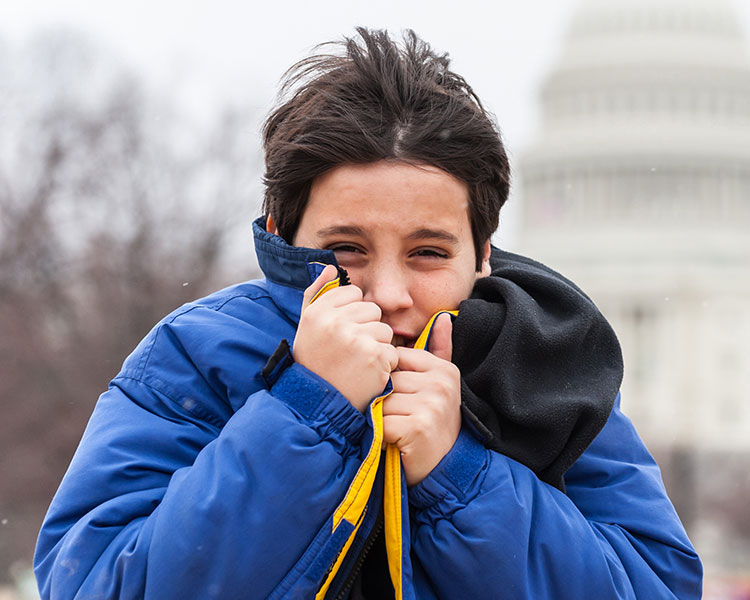 Photo of a kid using pulling their jacket in tighter to fight off the cold