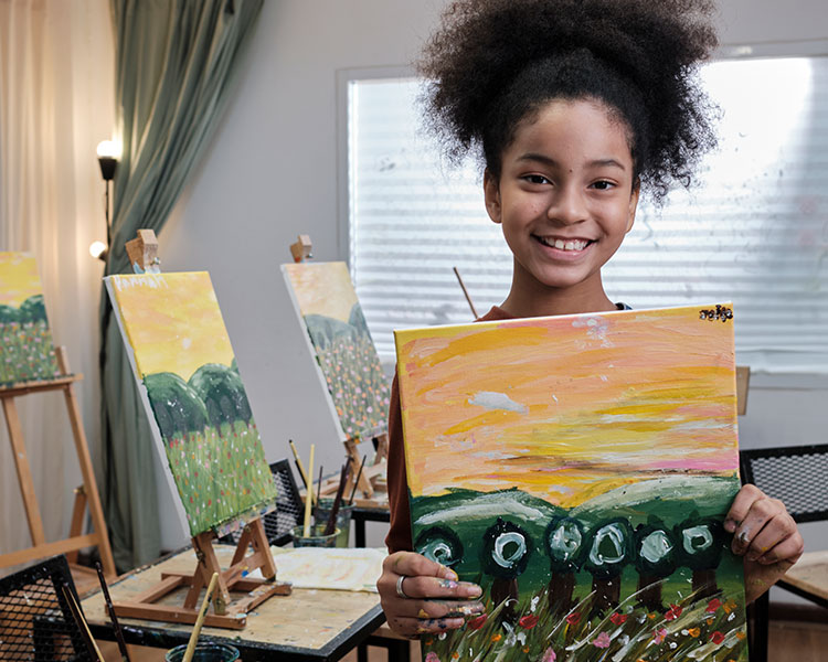 Image of student holding up painting and smiling