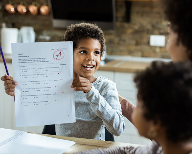 Photo of a son showing his parent the good grade he earned on his test