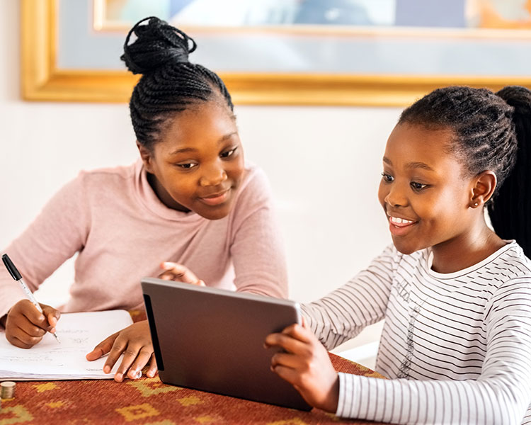 Photo of one student showing another something on their tablet