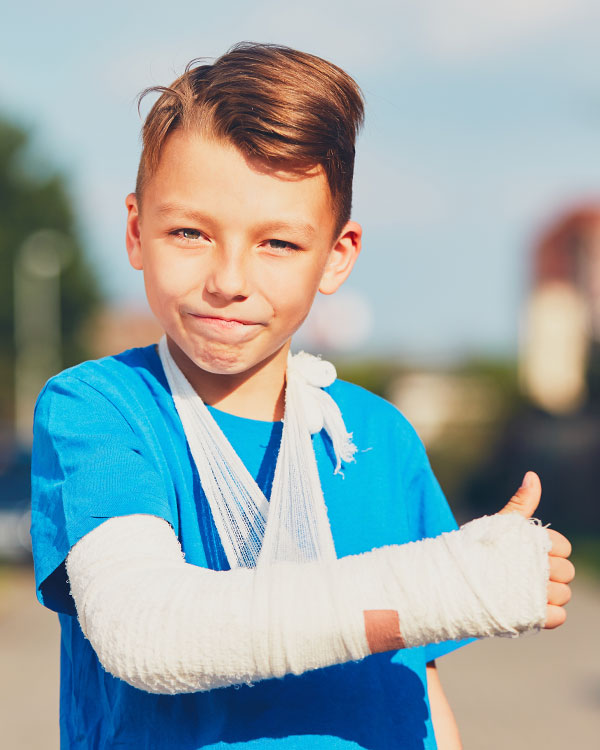 Photo of a kid with thumbs up wearing a cast on their arm