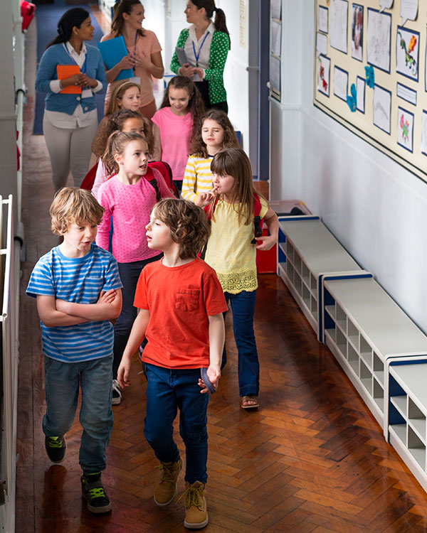 Photo of students walking in a school hallway with teachers following behind